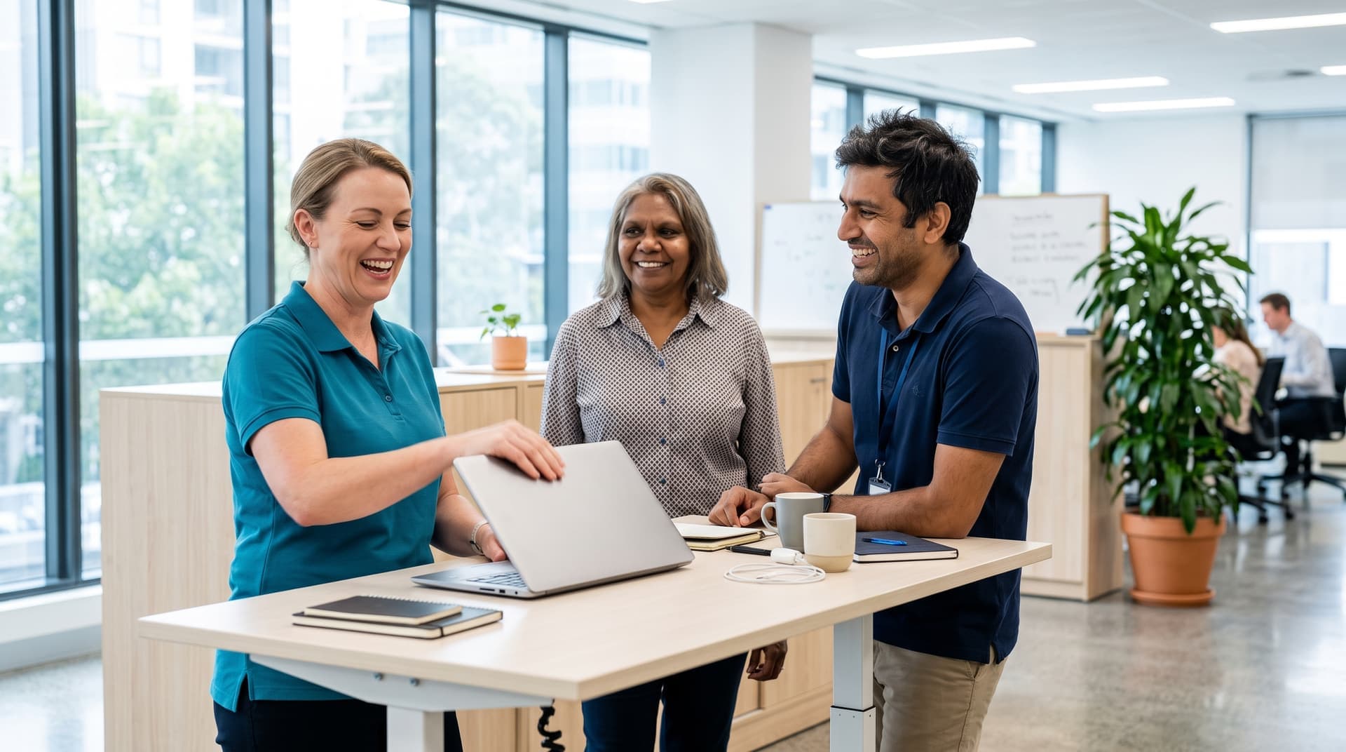 Three colleagues at a standing desk in a bright office, finishing up and laughing together
